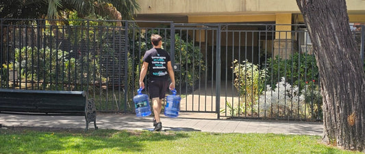 Repartidor de agua purificada premium entregando bidones en un departamento moderno en Santiago de Chile