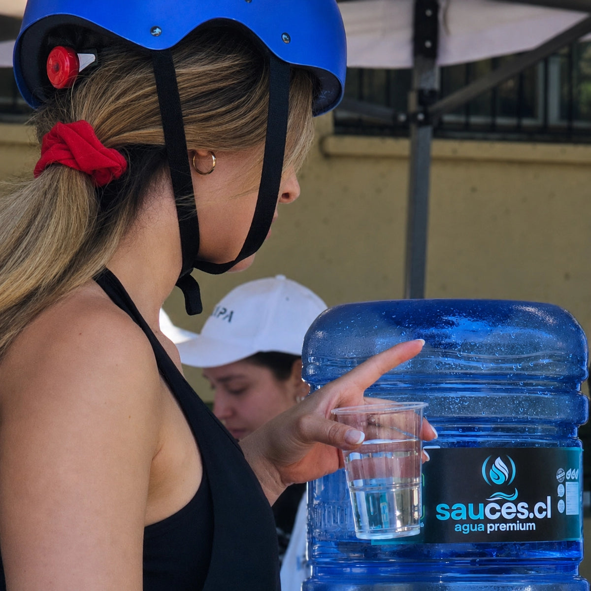 Persona sirviéndose agua purificada Sauces en punto de hidratación en Santiago