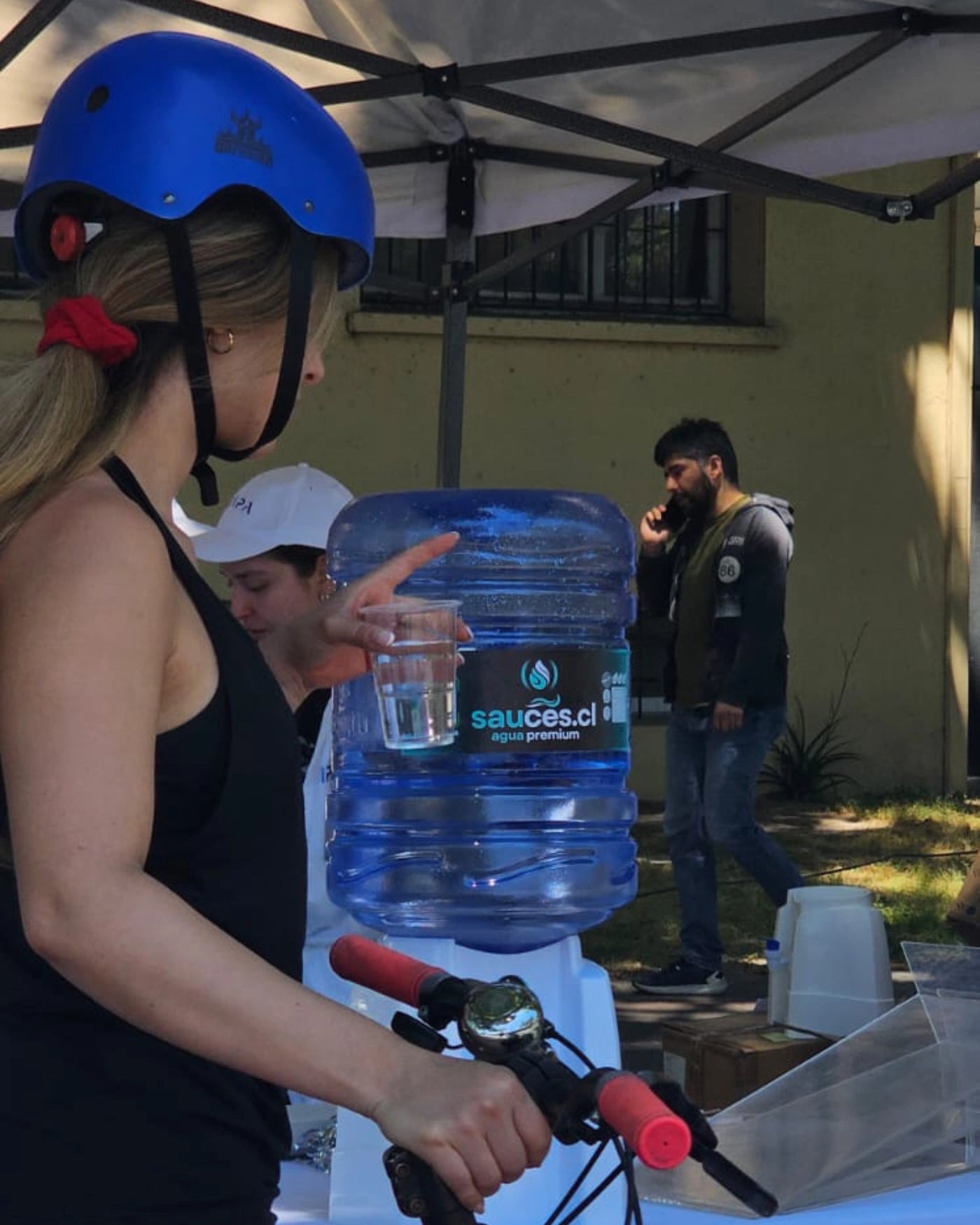 Ciclista tomando agua Sauces.cl en un punto de hidratación durante un evento deportivo